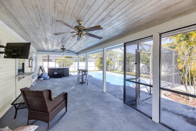 sunroom featuring a ceiling fan and a hot tub