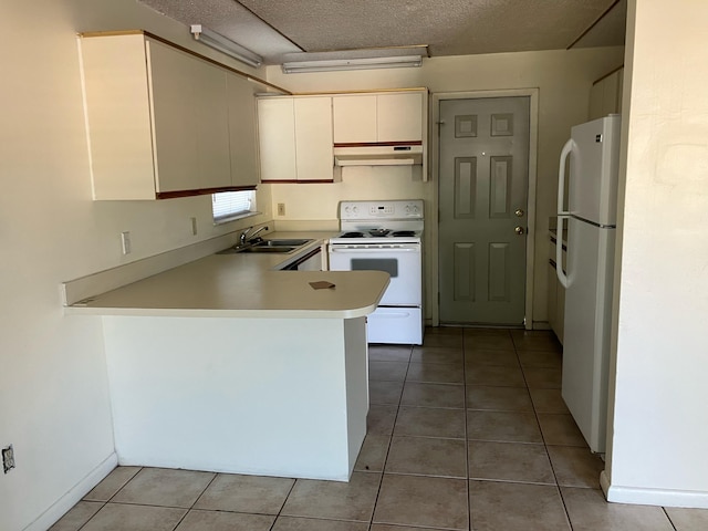kitchen with white appliances, a peninsula, light tile patterned flooring, under cabinet range hood, and a sink