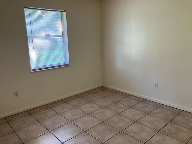 unfurnished room with light tile patterned floors and baseboards