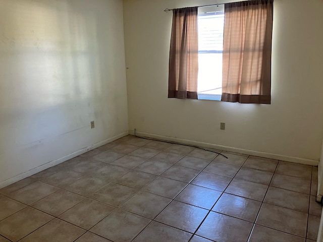 unfurnished room featuring light tile patterned flooring and baseboards