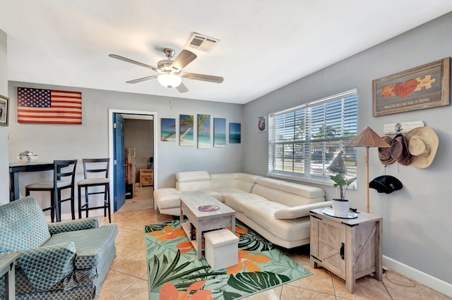living area featuring light tile patterned floors, a ceiling fan, visible vents, and baseboards