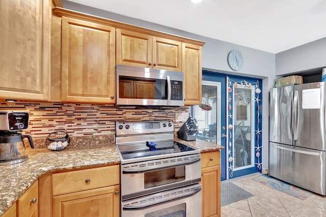 kitchen with light tile patterned floors, backsplash, appliances with stainless steel finishes, and light brown cabinetry