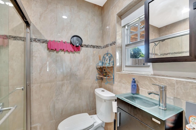 bathroom with vanity, tile walls, toilet, and a shower with door