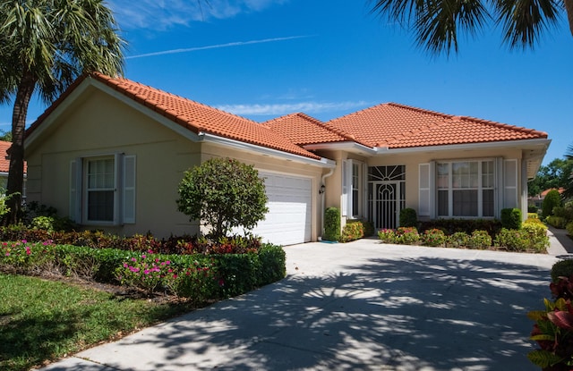 view of front of property featuring an attached garage, a tile roof, stucco siding, and concrete driveway