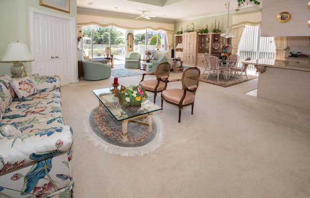 living room featuring carpet flooring, a ceiling fan, and ornamental molding