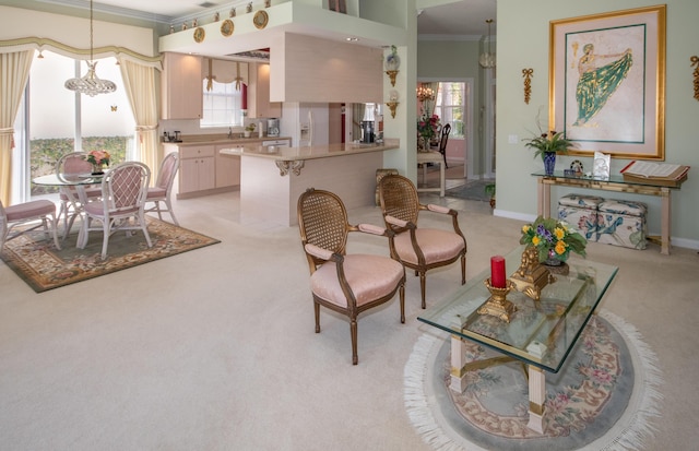 living area with light carpet, baseboards, a chandelier, and ornamental molding