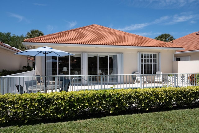 rear view of house featuring a tiled roof and stucco siding