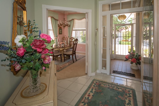 entryway with light colored carpet, a wealth of natural light, a notable chandelier, and light tile patterned floors