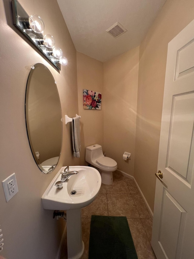 half bathroom featuring tile patterned floors, visible vents, toilet, and baseboards