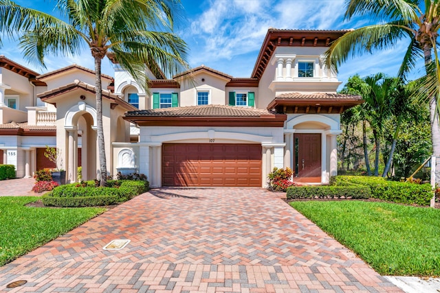 mediterranean / spanish house featuring stucco siding, decorative driveway, and a tiled roof