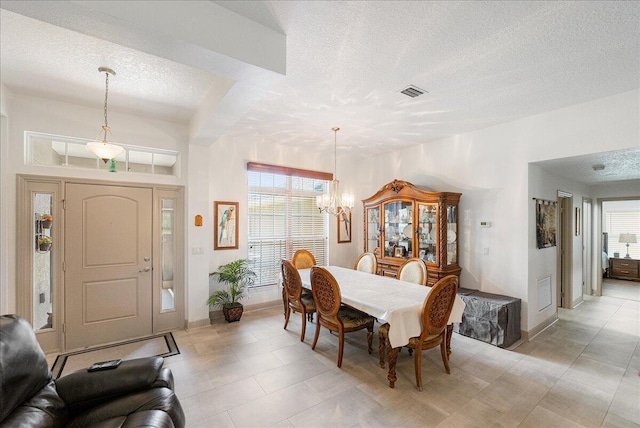 5879 NW Leah Dr, Port Saint Lucie, FL 34986 - dining space with a textured ceiling, a chandelier, and baseboards