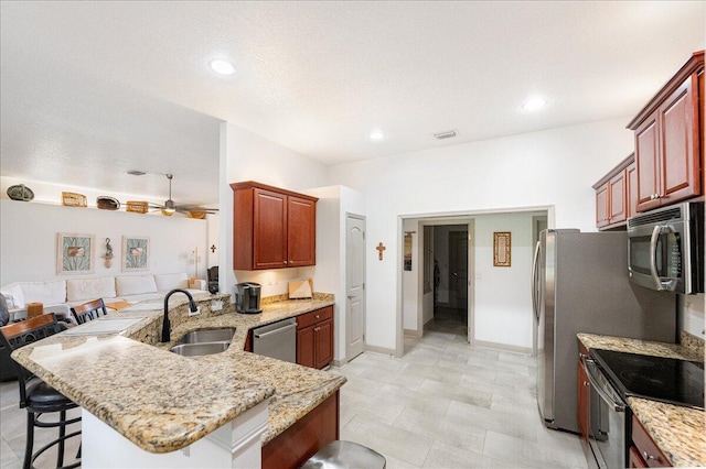5879 NW Leah Dr, Port Saint Lucie, FL 34986 - kitchen featuring appliances with stainless steel finishes, a sink, a kitchen bar, a peninsula, and light stone countertops