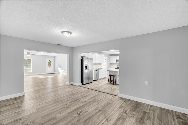 2244 Cooks Ct, Vero Beach, FL 32962 - unfurnished living room with light wood finished floors, a textured ceiling, baseboards, and ceiling fan