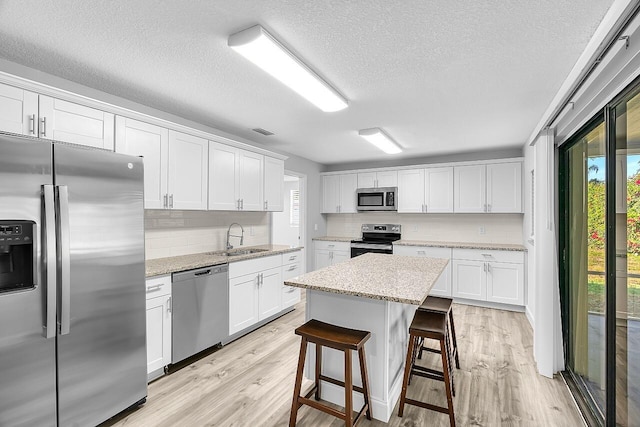 2244 Cooks Ct, Vero Beach, FL 32962 - kitchen with stainless steel appliances, a sink, plenty of natural light, white cabinetry, and a textured ceiling