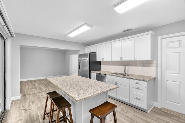 2244 Cooks Ct, Vero Beach, FL 32962 - kitchen featuring stainless steel appliances, a sink, a breakfast bar area, backsplash, and light wood-style flooring
