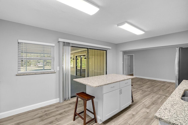 2244 Cooks Ct, Vero Beach, FL 32962 - kitchen featuring freestanding refrigerator, light wood-style floors, white cabinets, baseboards, and a center island
