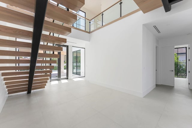 880 NE 3rd Ave, Boca Raton, FL 33432 - unfurnished living room featuring plenty of natural light, a high ceiling, baseboards, tile patterned flooring, and stairs