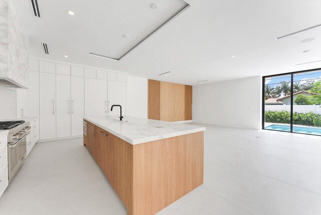 880 NE 3rd Ave, Boca Raton, FL 33432 - kitchen featuring modern cabinets, a sink, an island with sink, white cabinets, and light stone counters