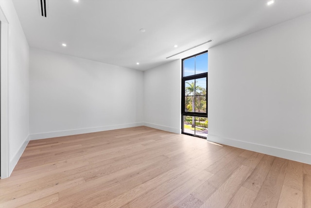 880 NE 3rd Ave, Boca Raton, FL 33432 - empty room with light wood finished floors, recessed lighting, baseboards, and a wall of windows