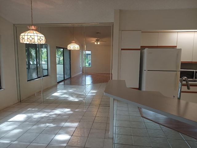2231 NW 34th Ter, Coconut Creek, FL 33066 - kitchen with white cabinetry, stainless steel microwave, light tile patterned floors, and freestanding refrigerator