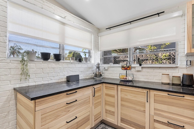 5400 NE 1st Ter, Oakland Park, FL 33334 - kitchen with tasteful backsplash, light brown cabinets, brick wall, and dark stone counters
