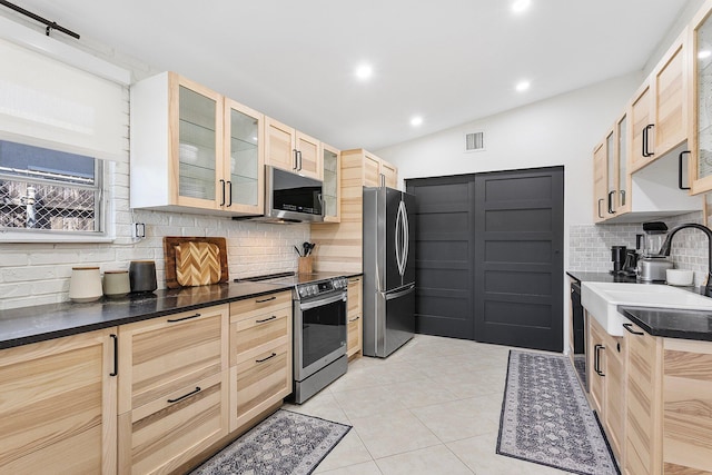 5400 NE 1st Ter, Oakland Park, FL 33334 - kitchen featuring dark countertops, visible vents, light brown cabinetry, stainless steel appliances, and a sink