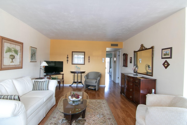 living area with baseboards, visible vents, and wood finished floors