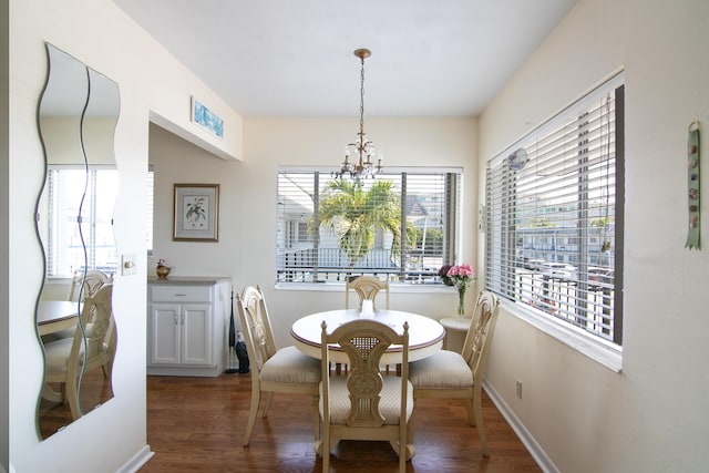 dining space with dark wood-type flooring, baseboards, and an inviting chandelier