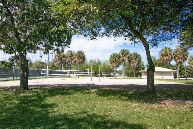 view of community with volleyball court, fence, and a lawn
