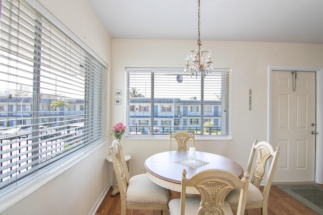 dining space with baseboards, a notable chandelier, and wood finished floors