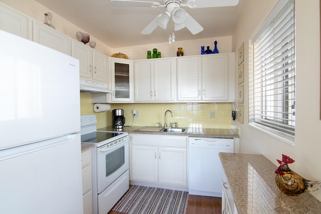 kitchen with backsplash, a sink, under cabinet range hood, white appliances, and white cabinets