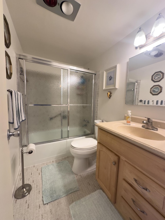 bathroom with toilet, shower / bath combination with glass door, and vanity