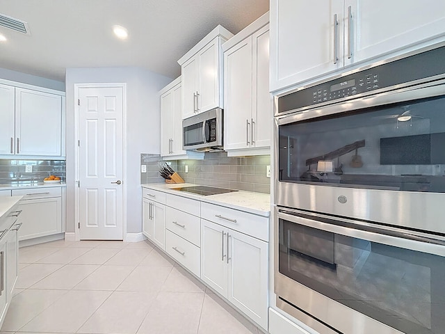 kitchen with visible vents, white cabinetry, appliances with stainless steel finishes, light tile patterned flooring, and decorative backsplash