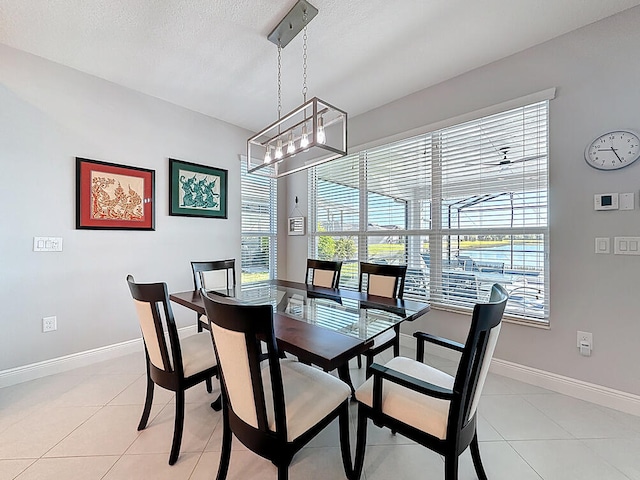 dining space with light tile patterned floors, baseboards, a textured ceiling, and an inviting chandelier