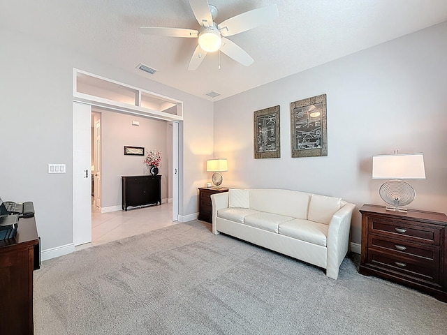 carpeted living area with visible vents, a textured ceiling, tile patterned flooring, baseboards, and ceiling fan