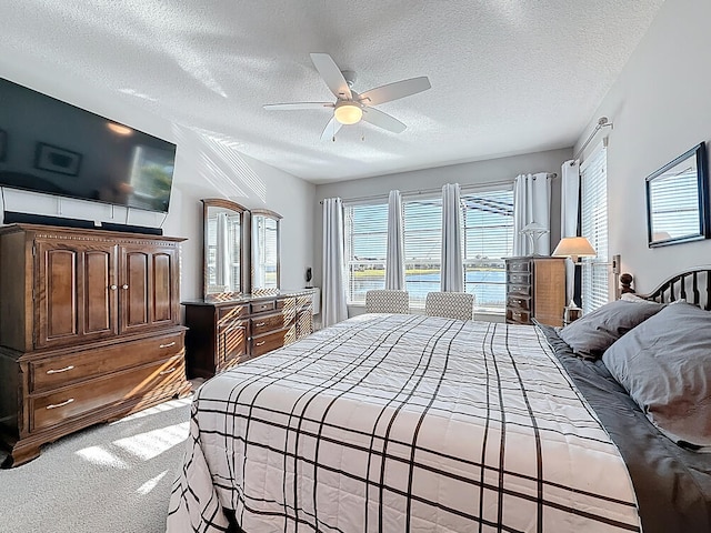 carpeted bedroom featuring a textured ceiling and a ceiling fan