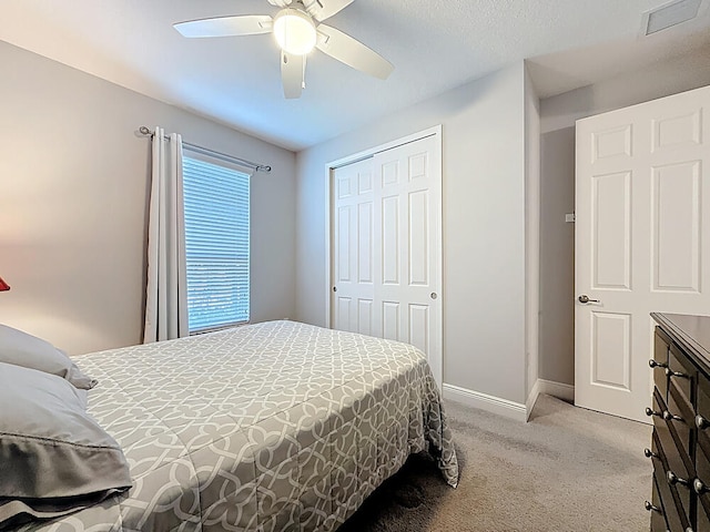carpeted bedroom featuring a closet, visible vents, a ceiling fan, and baseboards