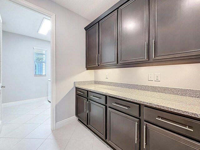 kitchen with light tile patterned floors, light countertops, and baseboards