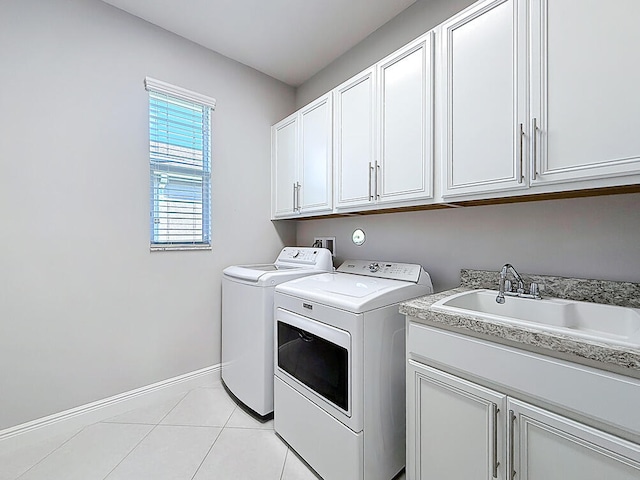 laundry room featuring a sink, cabinet space, separate washer and dryer, light tile patterned flooring, and baseboards