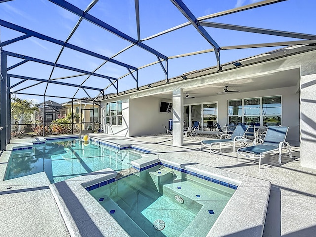 view of swimming pool with glass enclosure, a patio area, a pool with connected hot tub, and ceiling fan