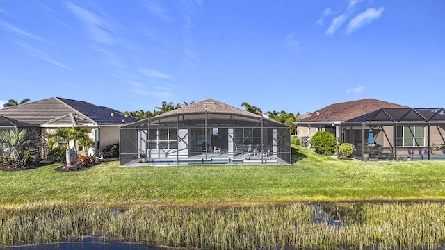 rear view of property featuring an outdoor pool, glass enclosure, a patio, and a lawn