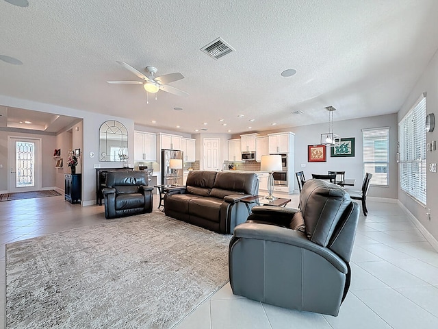 living room featuring light tile patterned floors, visible vents, plenty of natural light, and a ceiling fan