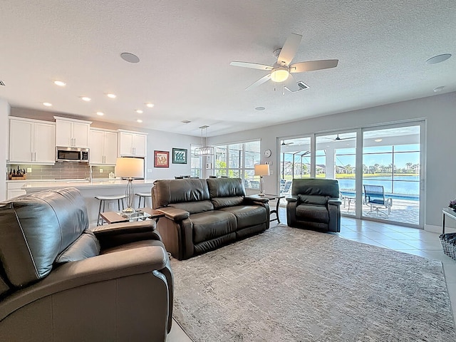 living room featuring a textured ceiling, light tile patterned flooring, recessed lighting, and ceiling fan