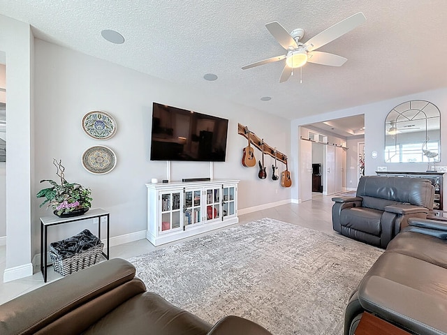 living area with baseboards, a textured ceiling, and ceiling fan