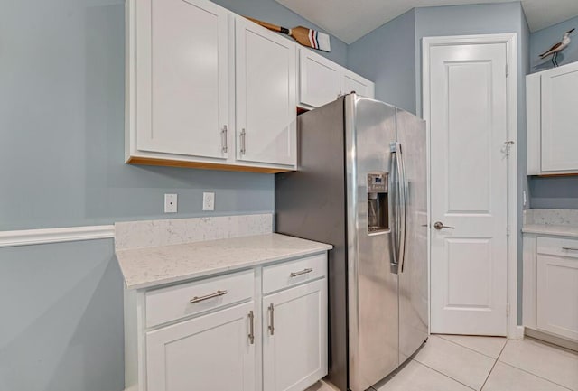 1012 Willow Pl, Riviera Beach, FL 33410 - kitchen with stainless steel fridge with ice dispenser, white cabinetry, light tile patterned flooring, and light stone countertops