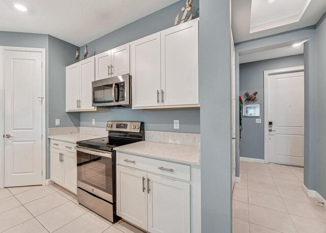 1012 Willow Pl, Riviera Beach, FL 33410 - kitchen featuring appliances with stainless steel finishes, light tile patterned floors, baseboards, white cabinets, and recessed lighting
