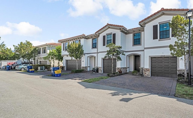 1012 Willow Pl, Riviera Beach, FL 33410 - view of front facade featuring stucco siding, a garage, decorative driveway, stone siding, and a tiled roof