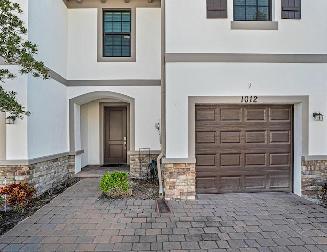 1012 Willow Pl, Riviera Beach, FL 33410 - doorway to property featuring stone siding, stucco siding, an attached garage, and decorative driveway