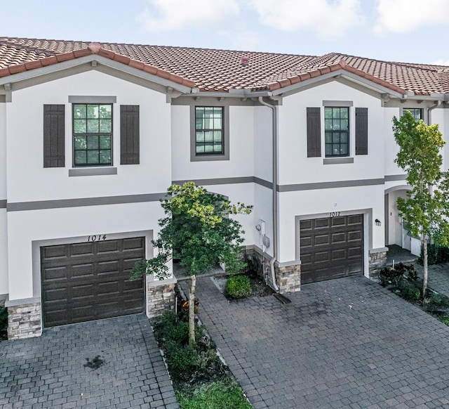 1012 Willow Pl, Riviera Beach, FL 33410 - view of front of home with an attached garage, stone siding, decorative driveway, stucco siding, and a tile roof