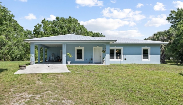 7633 NW 93rd Ct, Okeechobee, FL 34972 - back of property featuring stucco siding, metal roof, driveway, an attached carport, and a yard